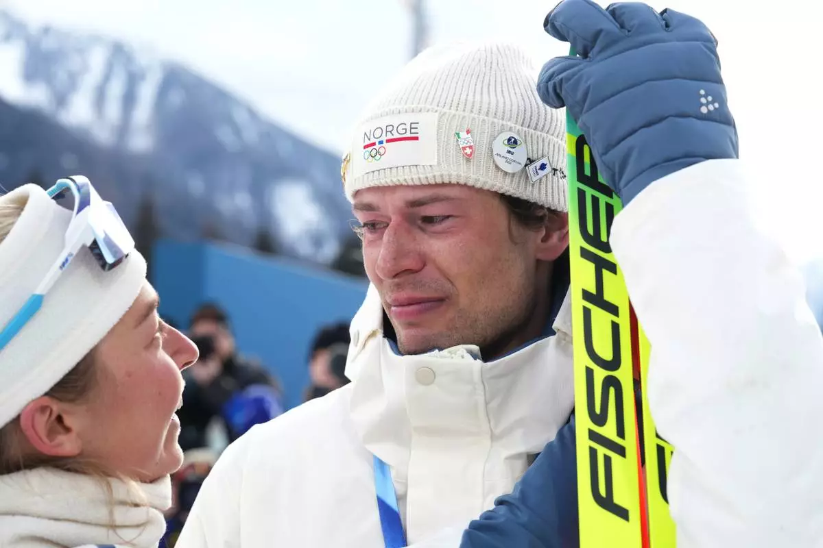 ADDS NAME OF TEAMMATE - Sturla Holm Laegreid, of Norway, reacts after he won bronze as teammate Ingrid Landmark Tandrevold comforts him after the men's 20-kilometer individual biathlon race at the 2026 Winter Olympics in Anterselva, Italy, Tuesday, Feb. 10, 2026. (AP Photo/Andrew Medichini)
