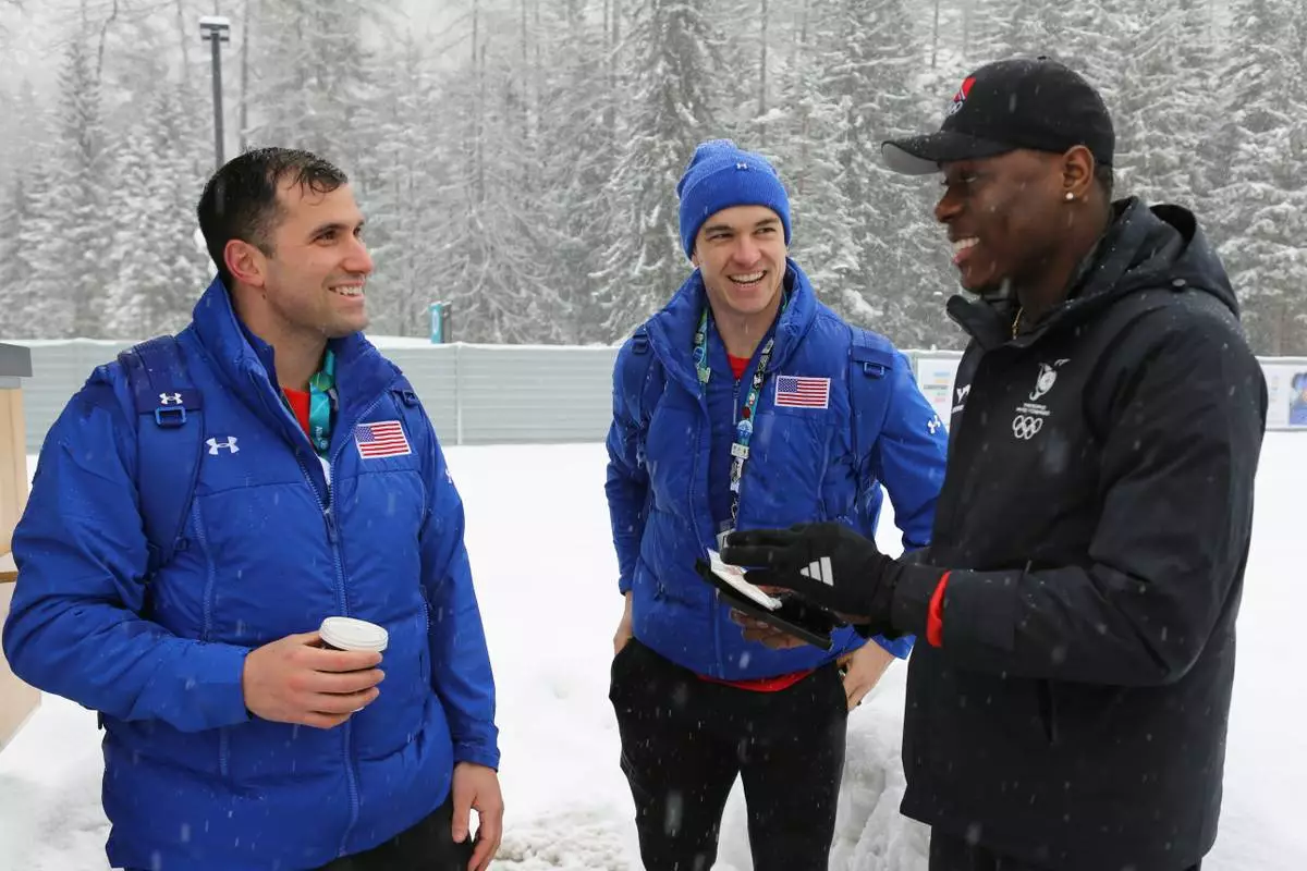 United States' bobsledders Frank Del Duca, left and Boone Niederhofer speak with De Aundre John, right, a bobsledder from Trinidad and Tobago after trading their unique national team pins, at the Cortina Olympic Village, during the 2026 Winter Olympics, in Cortina d'Ampezzo, Italy, Tuesday, Feb. 3, 2026. (AP Photo/Jennifer McDermott)