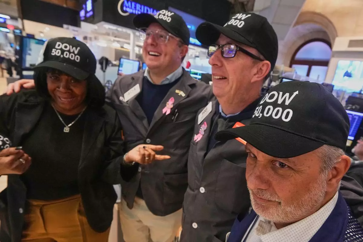 Trader Joel Lucchese, right, and colleagues wear "DOW 50,000" caps on the floor of the New York Stock Exchange as the Dow Jones industrial average intra-day number topped the 50,000 level for the first time, Friday, Feb. 6, 2026. (AP Photo/Richard Drew)