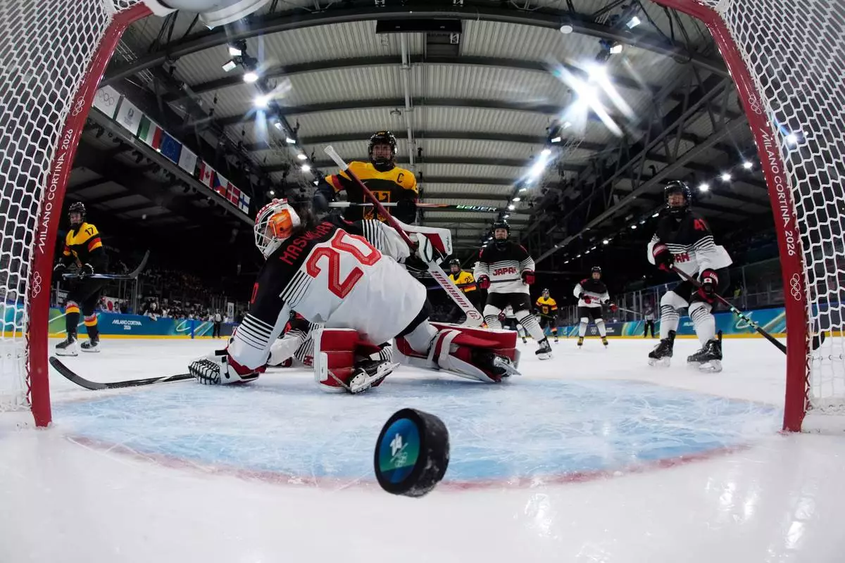Germany's Emily Nix, left, scores her side's third goal during a preliminary round match of women's ice hockey between Germany and Japan at the 2026 Winter Olympics, in Milan, Italy, Saturday, Feb. 7, 2026. (AP Photo/Darko Bandic, Pool)