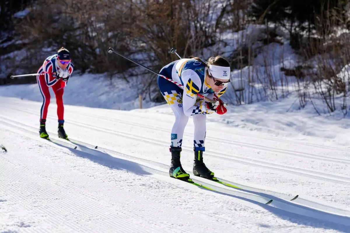 Ebba Andersson, of Sweden, leads Heidi Weng, of Norway, during the cross country skiing women's 50km mass start classic at the 2026 Winter Olympics, in Tesero, Italy, Sunday, Feb. 22, 2026. (AP Photo/Evgeniy Maloletka)