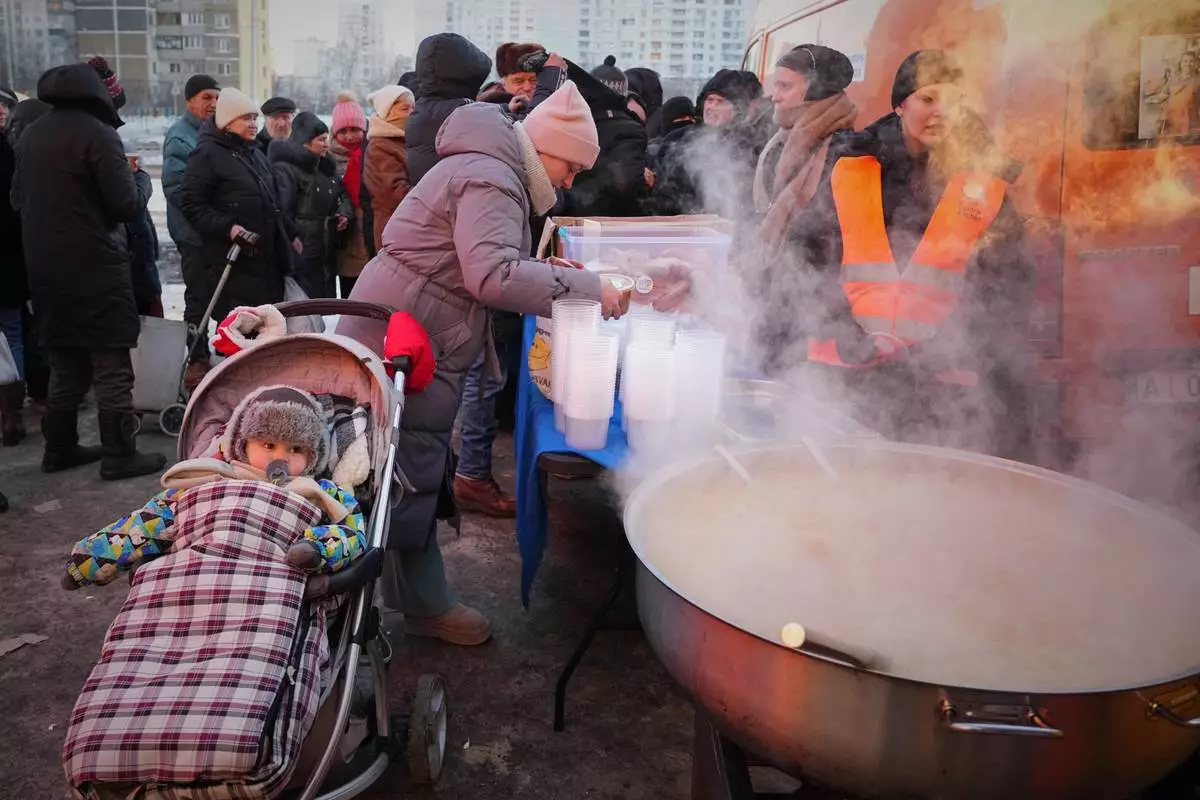 Yuliia Dolotova, 37, receives hot food at a distribution point during a power outage caused by Russia’s repeated air strikes on the country’s power grid, in Kyiv, Ukraine, Monday, Feb. 2, 2026. (AP Photo/Sergey Grits)