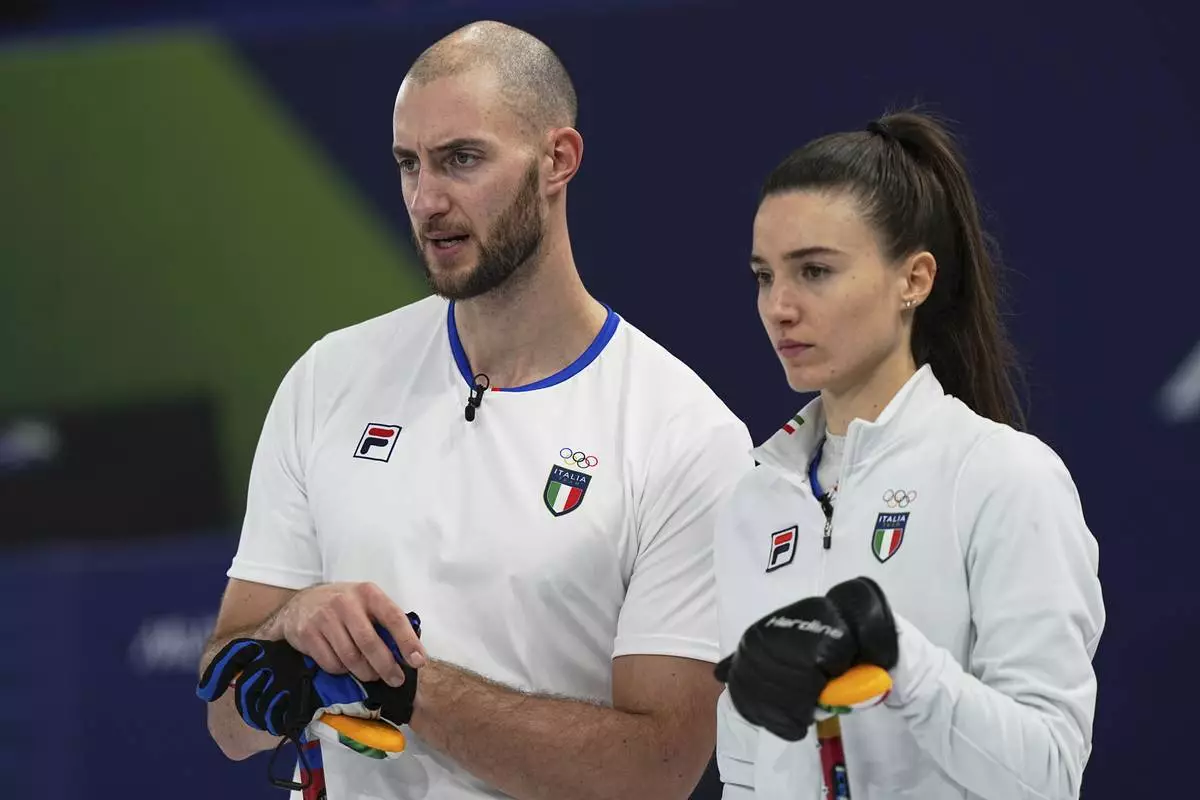 Italy's Amos Mosaner, left, and Stefania Constantini strategize during the mixed doubles round robin phase of the curling competition against Norway at the 2026 Winter Olympics, in Cortina d'Ampezzo, Italy, Saturday, Feb. 7, 2026. (AP Photo/Fatima Shbair)
