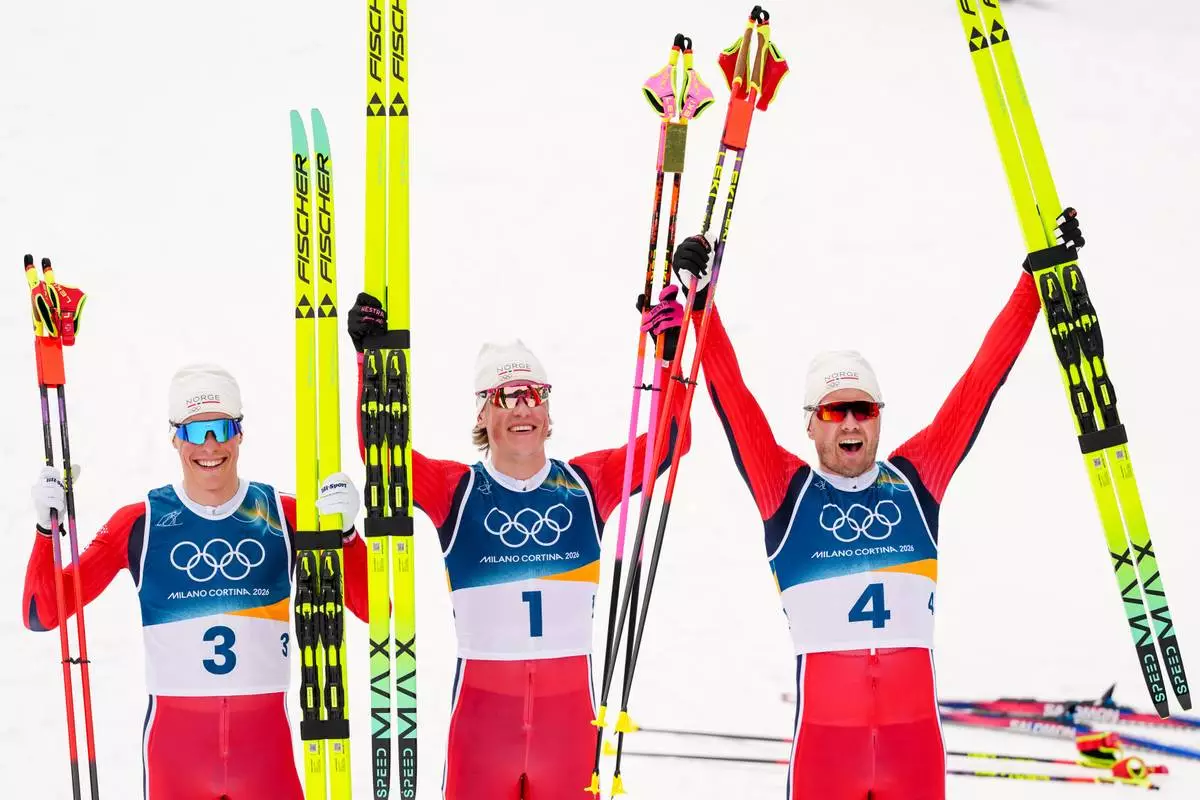 Silver medalist Martin Loewstroem Nyenget, gold medalist Johannes Hoesflot Klaebo and bronze medalist Emil Iversen, all three of Norway, pose after the cross country skiing men's 50km mass start Classic at the 2026 Winter Olympics, in Tesero, Italy, Saturday, Feb. 21, 2026. . (AP Photo/Kirsty Wigglesworth)