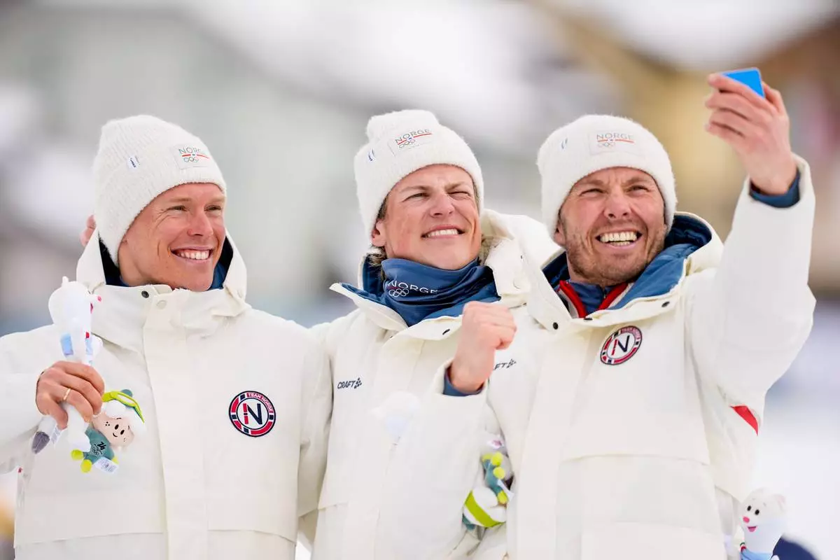 Silver medalist Martin Loewstroem Nyenget, gold medalist Johannes Hoesflot Klaebo and bronze medalist Emil Iversen, all three of Norway, pose on the podium of the cross country skiing men's 50km mass start Classic at the 2026 Winter Olympics, in Tesero, Italy, Saturday, Feb. 21, 2026. (AP Photo/Matthias Schrader)