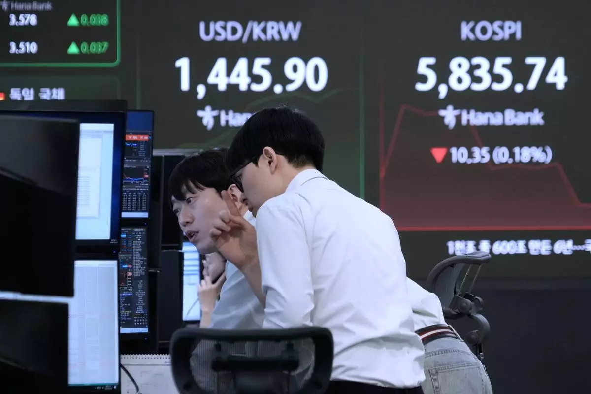 Currency traders watch monitors near a screen showing the Korea Composite Stock Price Index (KOSPI), right, and the foreign exchange rate between U.S. dollar and South Korean won at the foreign exchange dealing room of the Hana Bank headquarters in Seoul, South Korea, Tuesday, Feb. 24, 2026. (AP Photo/Ahn Young-joon)