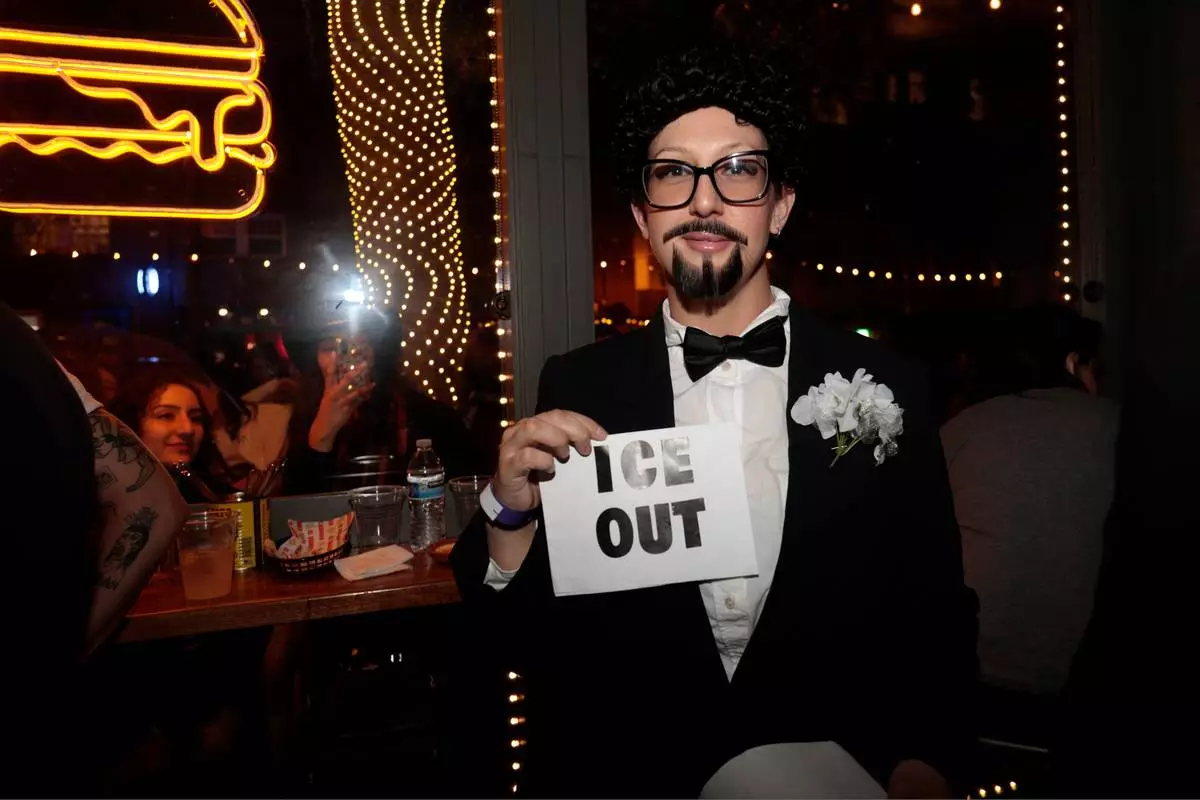 A contestant at the Bad Bunny look-alike contestholds an "ICE OUT" sign throughout the evening at Tacolicious in San Francisco, Thursday, Feb. 5, 2026. (Giselle Garza Lerma/San Francisco Chronicle via AP)