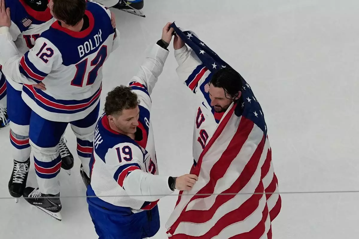 United States' Matthew Tkachuk (19) helps put an American flag around goalie Connor Hellebuyck after the United States beat Canada in overtime to win the men's gold medal hockey game at the 2026 Winter Olympics, in Milan, Italy, Sunday, Feb. 22, 2026. (AP Photo/David J. Phillip)
