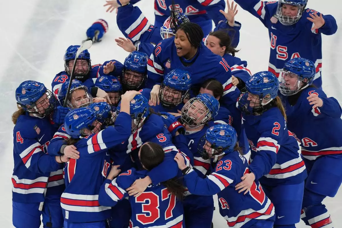United States players surround Megan Keller (5) after she scored the winning goal in overtime to beat Canada in the women's ice hockey gold medal game at the 2026 Winter Olympics, in Milan, Italy, Feb. 19, 2026. (AP Photo/Carolyn Kaster, File)