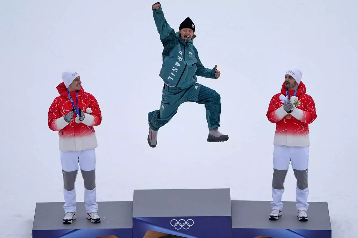 Brazil's Lucas Pinheiro Braathen, center, winner of an alpine ski, men's giant slalom race, jumps in celebration on the podium flanked by second-place Switzerland's Marco Odermatt, left, and third-place Switzerland's Loic Meillard, at the 2026 Winter Olympics, in Bormio, Italy, Feb. 14, 2026. (AP Photo/John Locher, File)