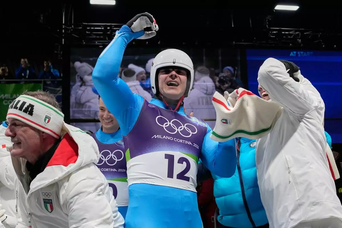 Italy's Dominik Fischnaller, center, celebrates winning the bronze medal as he arrives at the finish during a men's single luge run at the 2026 Winter Olympics, in Cortina d'Ampezzo, Italy, Sunday, Feb. 8, 2026. (AP Photo/Alessandra Tarantino)
