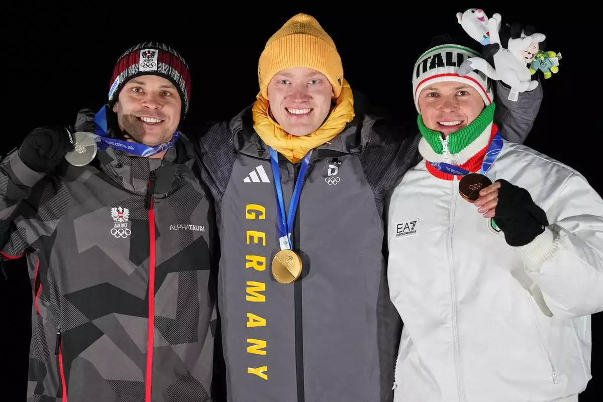 From left, second placed Austria's Jonas Mueller, first placed Germany's Max Langenhan and third placed Italy's Dominik Fischnaller pose with their medals after the men's single luge competition at the 2026 Winter Olympics, in Cortina d'Ampezzo, Italy, Sunday, Feb. 8, 2026. (AP Photo/Alessandra Tarantino)