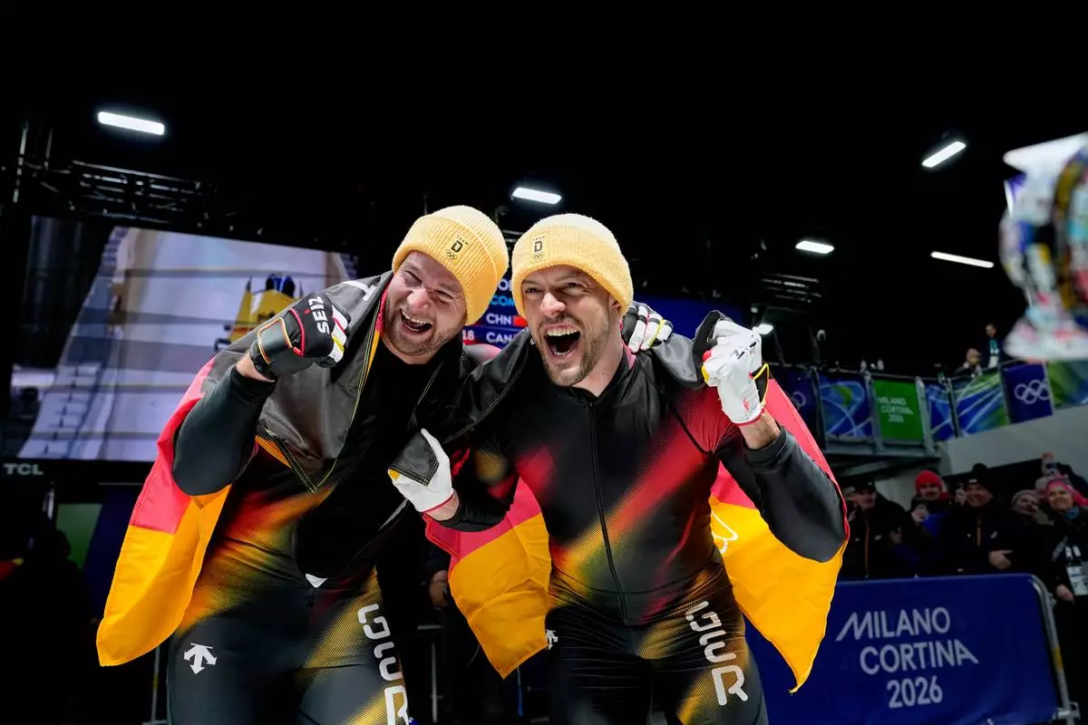 Germany's gold medalists Johannes Lochner, left, and Georg Fleischhauer celebrate at the finish after the two man bobsled competition at the 2026 Winter Olympics, in Cortina d'Ampezzo, Italy, Tuesday, Feb. 17, 2026. (AP Photo/Alessandra Tarantino)
