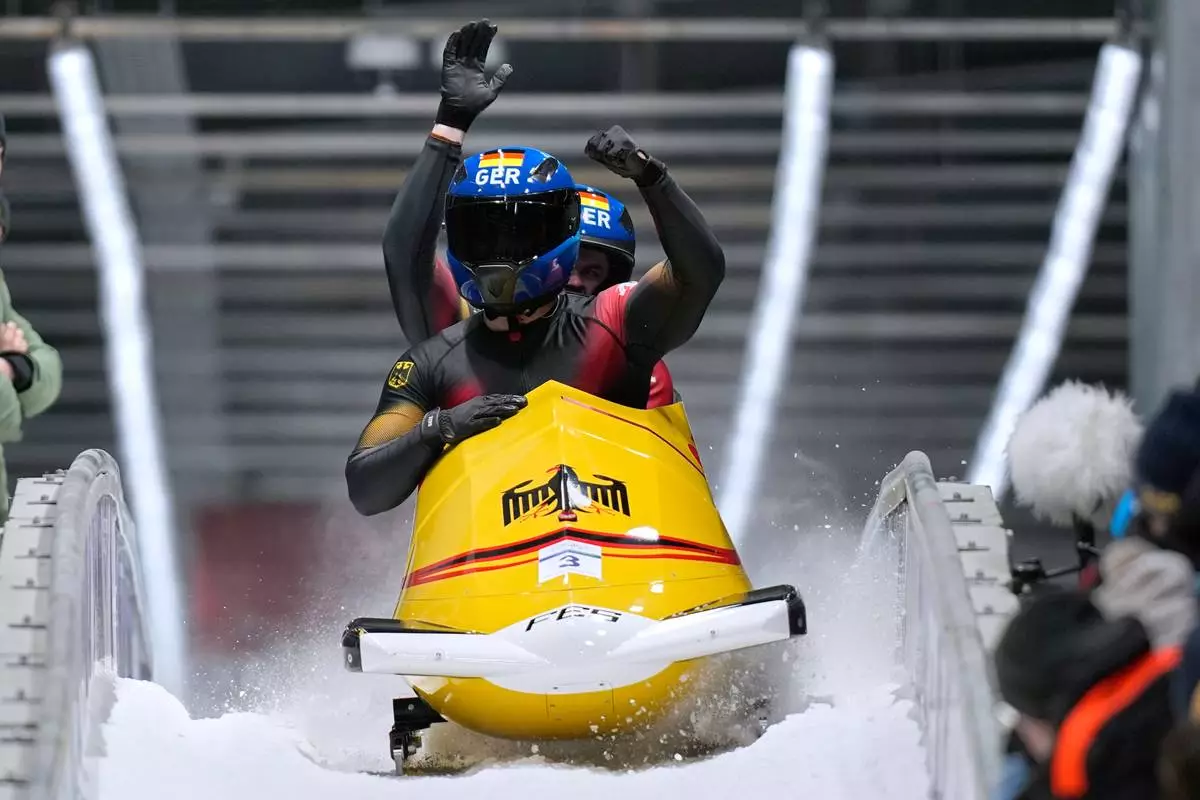 Germany's Adam Ammour, front, and Alexander Schaller arrive at the finish during a two man bobsled run at the 2026 Winter Olympics, in Cortina d'Ampezzo, Italy, Tuesday, Feb. 17, 2026. (AP Photo/Aijaz Rahi)