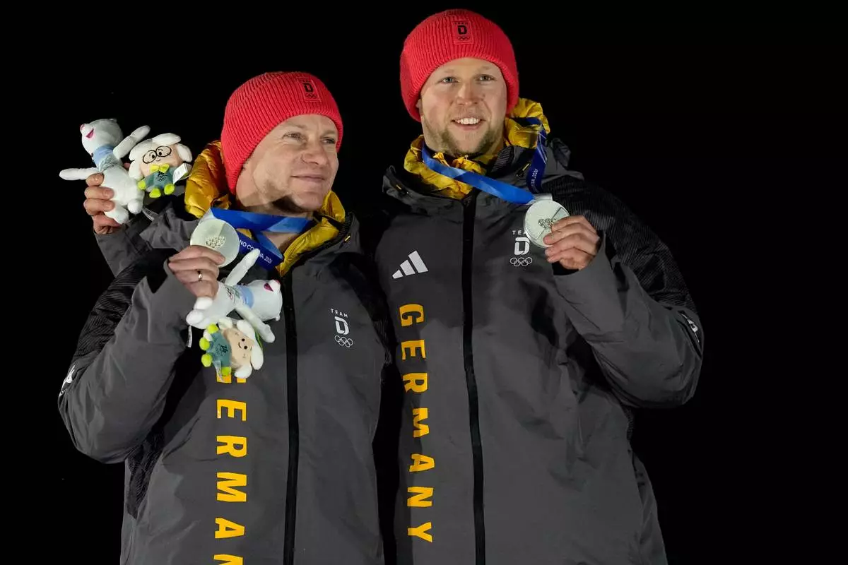 Germany's silver medalists Francesco Friedrich, left, and Alexander Schuller, right, pose with their medals after the two man bobsled competition at the 2026 Winter Olympics, in Cortina d'Ampezzo, Italy, Tuesday, Feb. 17, 2026. (AP Photo/Alessandra Tarantino)