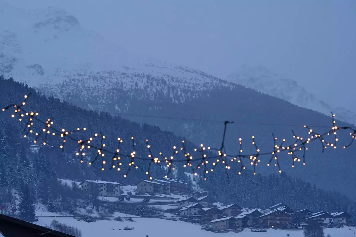 Houses perched on the mountain alongside Stelvio Ski Centre are seen past town lights in Bormio, Italy, at the 2026 Winter Olympics, Wednesday, Feb. 4, 2026. (AP Photo/Rebecca Blackwell)