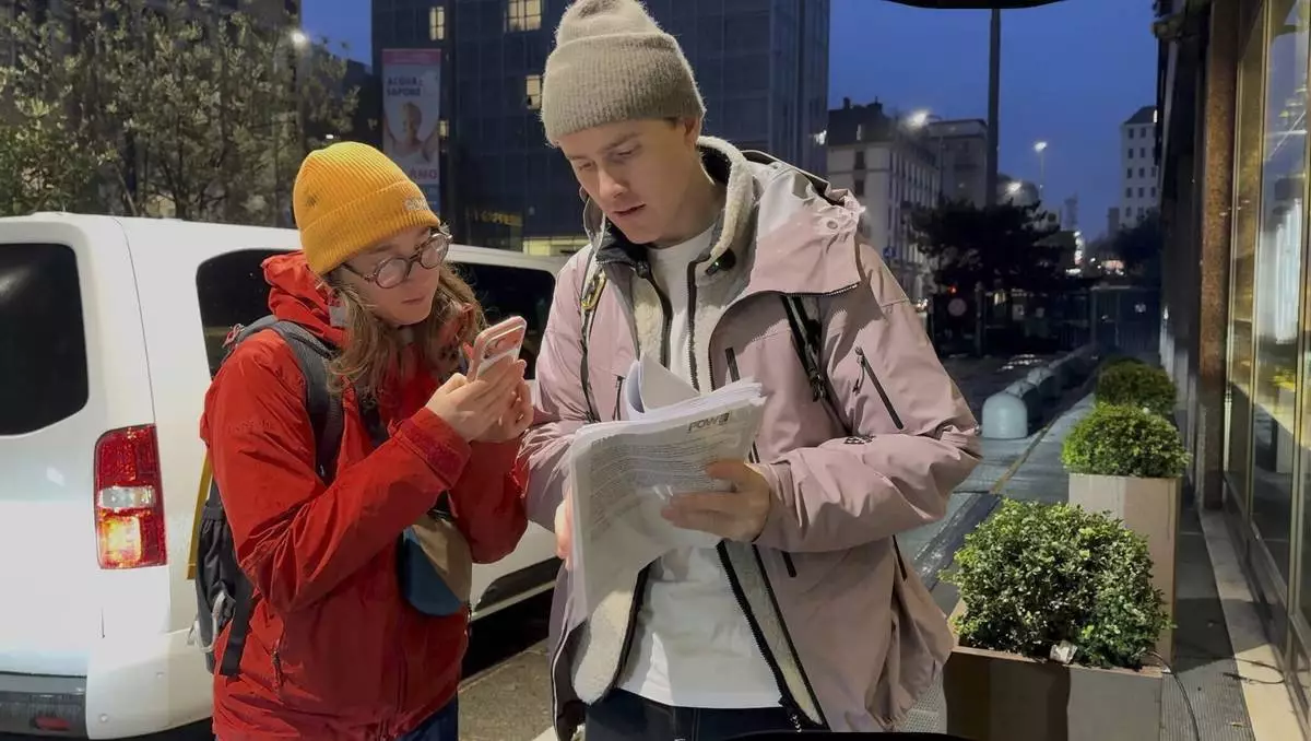 Norwegian skier Nikolai Schirmer and Protect Our Winters Italy General Manager Giorgio Garancini look over a “ski fossil free” petition with over 20,000 signatures that Schirmer privately handed to the IOC's head of sustainability, Julie Duffus, two days before the Opening Ceremony for the 2026 Milan Cortina Winter Olympics, Wednesday, Feb. 4, 2026, in Milan. (AP Photo/Fernanda Figueroa)