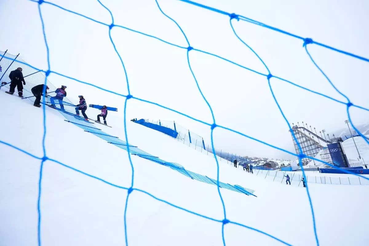 Workers set up fencing along the slopestyle course before a training session at the 2026 Winter Olympics, in Livigno, Italy, Wednesday, Feb. 4, 2026. (AP Photo/Gregory Bull)