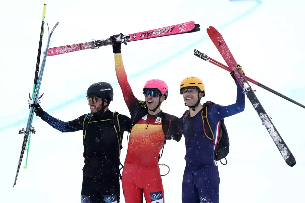 Spain's Oriol Cardona Coll, center, celebrates winning the gold medal in a ski mountaineering men's sprint final, with silver medalist Individual Neutral Athlete Nikita Filippov, left, and bronze medalist France's Thibault Anselmet, at the 2026 Winter Olympics, in Bormio, Italy, Thursday, Feb. 19, 2026. (AP Photo/Gabriele Facciotti)