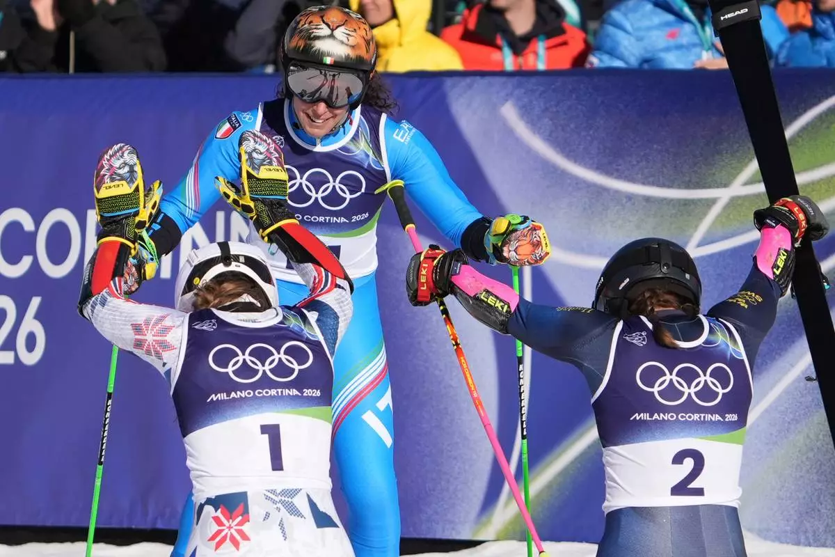 Sweden's Sara Hector, right, and Norway's Thea Louise Stjernesund bow to Italy's Federica Brignone, center, at the finish area of an alpine ski, women's giant slalom race, at the 2026 Winter Olympics, in Cortina d'Ampezzo, Italy, Sunday, Feb. 15, 2026. (AP Photo/Jacquelyn Martin)