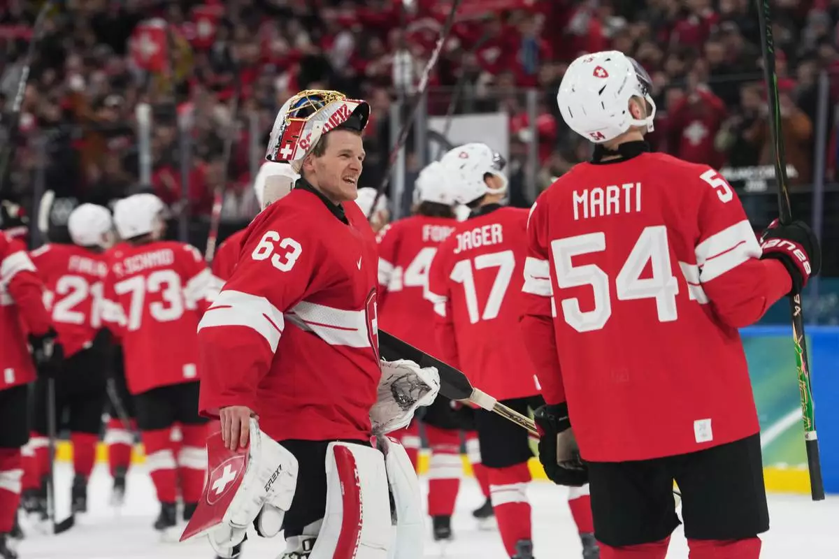 Switzerland's goalkeeper Leonardo Genoni, right, celebrates with teammates after a preliminary round match of men's ice hockey between Switzerland and France at the 2026 Winter Olympics, in Milan, Italy, Thursday, Feb. 12, 2026. (AP Photo/Carolyn Kaster)
