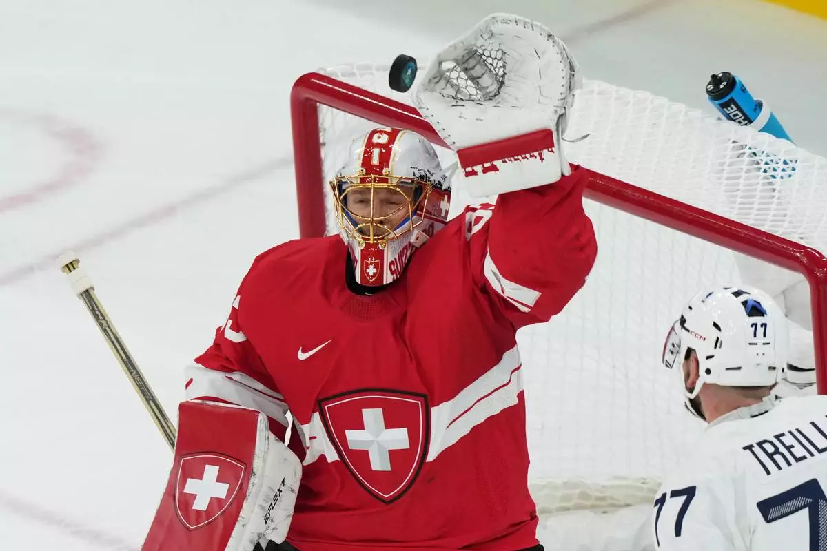 Switzerland's goalkeeper Leonardo Genoni , makes a save during a preliminary round match of men's ice hockey between Switzerland and France at the 2026 Winter Olympics, in Milan, Italy, Thursday, Feb. 12, 2026. (AP Photo/Carolyn Kaster)