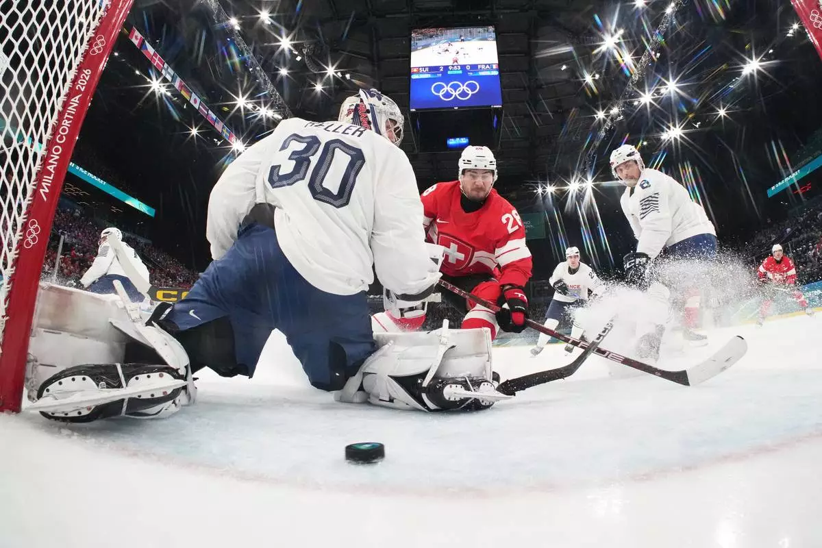 Switzerland's Timo Meier, center, scores his sides third goal past France's goalkeeper Antoine Keller during a preliminary round match of men's ice hockey between Switzerland and France at the 2026 Winter Olympics, in Milan, Italy, Thursday, Feb. 12, 2026. (Mike Segar/Pool Photo via AP)