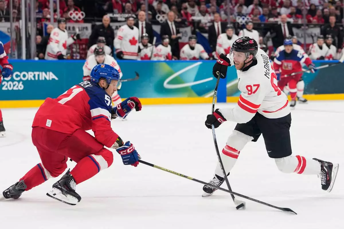 Czechia's Radim Simek tries to block a shot by Canada's Connor McDavid during a preliminary round match of men's ice hockey between Czech Republic and Canada at the 2026 Winter Olympics, in Milan, Italy, Thursday, Feb. 12, 2026. (AP Photo/Petr David Josek)