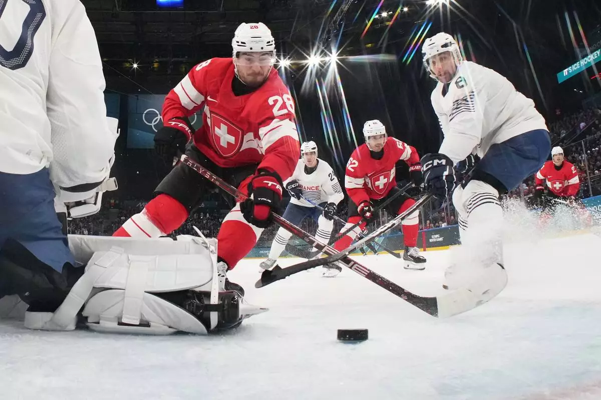 Switzerland's Timo Meier, center, scores his sides third goal past France's goalkeeper Antoine Keller during a preliminary round match of men's ice hockey between Switzerland and France at the 2026 Winter Olympics, in Milan, Italy, Thursday, Feb. 12, 2026. (Mike Segar/Pool Photo via AP)
