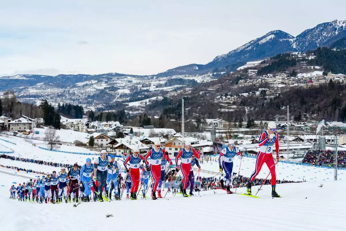 Martin Loewstroem Nyenget, of Norway, right, leads at the start of the cross country skiing men's 50km mass start Classic at the 2026 Winter Olympics, in Tesero, Italy, Saturday, Feb. 21, 2026. (AP Photo/Evgeniy Maloletka)