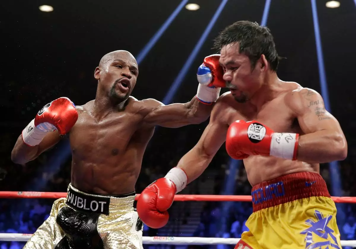 FILE - Floyd Mayweather Jr., left, hits Manny Pacquiao, from the Philippines, during their welterweight title fight on May 2, 2015, in Las Vegas. (AP Photo/Isaac Brekken, File)