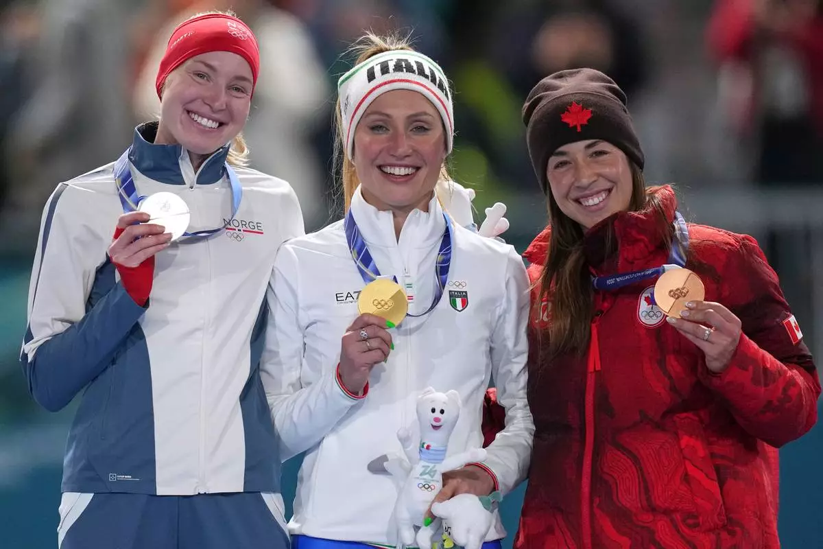 Francesca Lollobrigida of Italy, center and gold medal celebrates with Ragne Wiklund of Norway, left and silver medal, and Valerie Maltais of Canada, right and bronze medal, on the podium of the women's 3,000 meters speedskating race at the 2026 Winter Olympics, in Milan, Italy, Saturday, Feb. 7, 2026. (AP Photo/Christophe Ena)