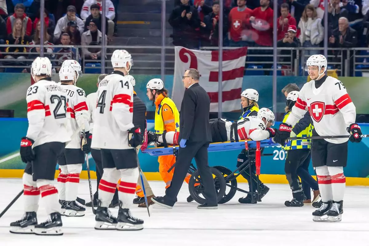 Injured Switzerland's Kevin Fiala is stretchered off the ice by paramedics, during a preliminary round match of men's ice hockey between Canada and Switzerland at the 2026 Winter Olympics, in Milan, Italy, Friday, Feb. 13, 2026. (Salvatore Di Nolfi/The Canadian Press via AP)