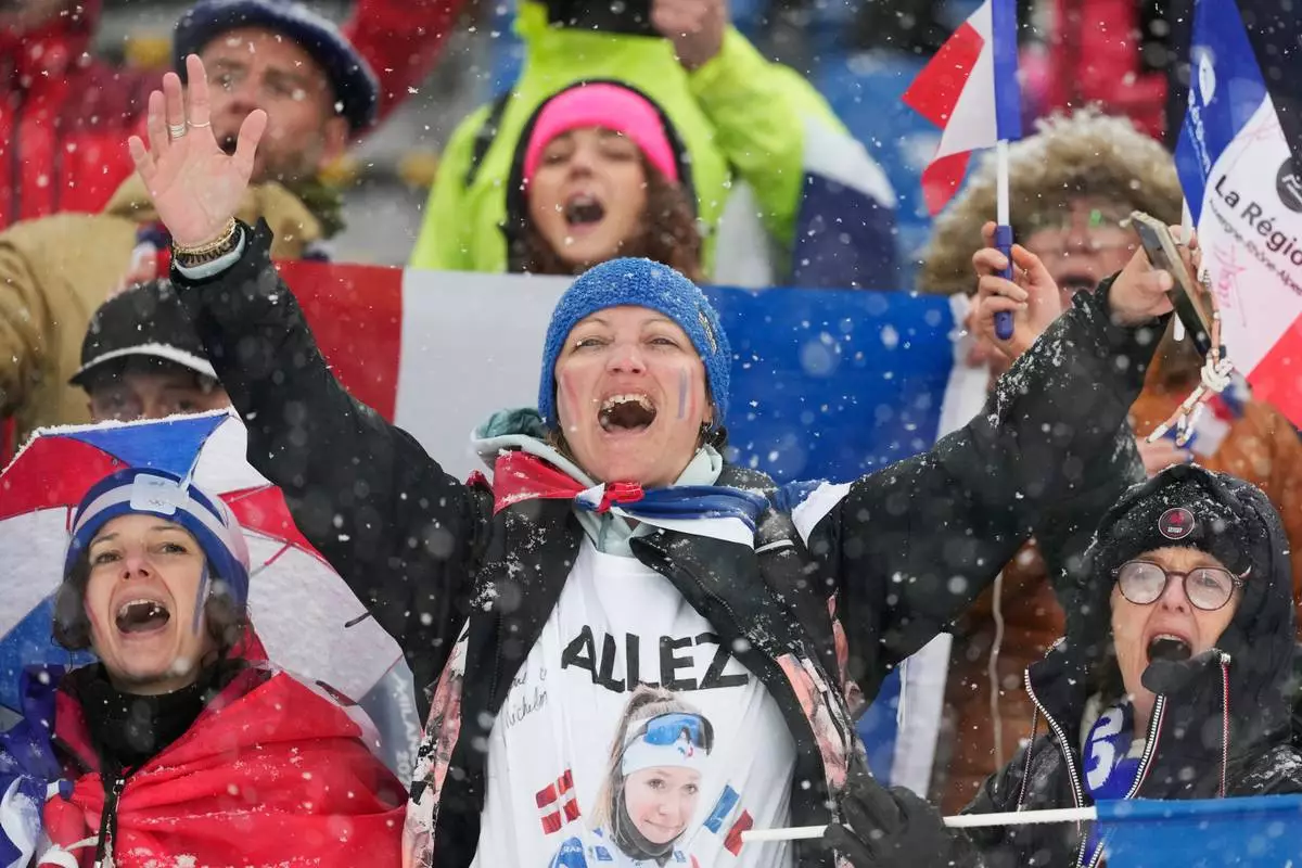 Fans of France celebrate after Julia Simon, of France, won silver and Oceane Michelon, of France, won gold in the women's 12.5-kilometer mass start biathlon race at the 2026 Winter Olympics in Anterselva, Italy, Saturday, Feb. 21, 2026. (AP Photo/Mosa'ab Elshamy)