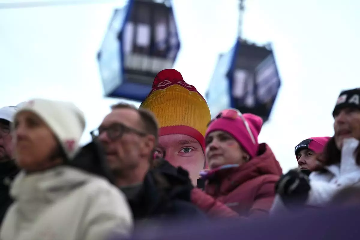 People hold a giant portrait of Germany's Max Langenhan in the finish area during a men's single luge run at the 2026 Winter Olympics, in Cortina d'Ampezzo, Italy, Sunday, Feb. 8, 2026. (AP Photo/Alessandra Tarantino)