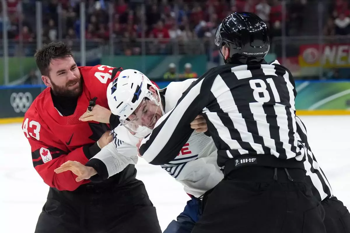 Canada's Tom Wilson (43) and France's Pierre Crinon, center, fight in the third period during a preliminary round game of men's ice hockey between Canada and France at the 2026 Winter Olympics, in Milan, Italy, Sunday, Feb. 15, 2026. (Nathan Denette/The Canadian Press via AP)
