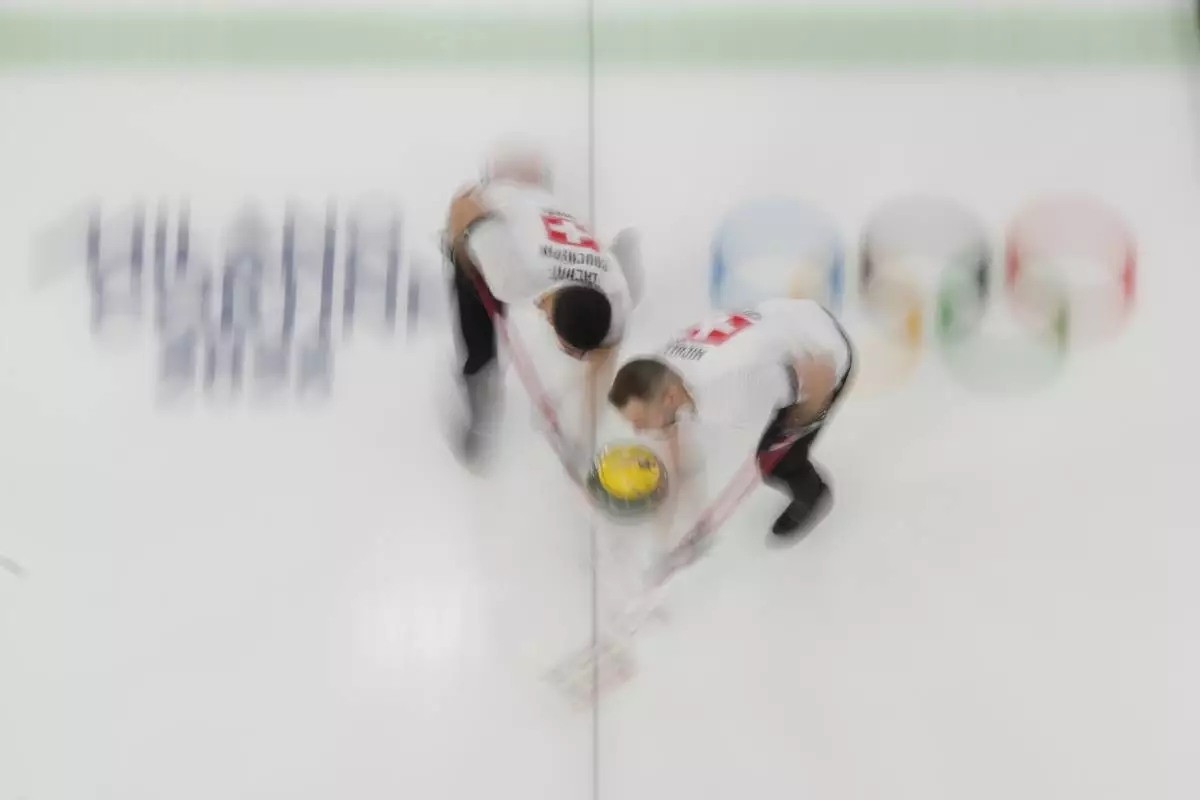Switzerland's Pablo Lachat-Couchepin and Sven Michel sweep ahead of the stone during a men's curling round robin match against the United States at the 2026 Winter Olympics, in Cortina d'Ampezzo, Italy, Thursday, Feb. 12, 2026. (AP Photo/David J. Phillip)