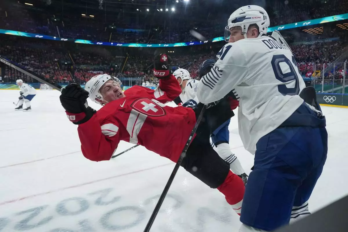 France's Floran Douay, right, checks Switzerland's Dean Kukan during a preliminary round match of men's ice hockey between Switzerland and France at the 2026 Winter Olympics, in Milan, Italy, Thursday, Feb. 12, 2026. (AP Photo/Carolyn Kaster)