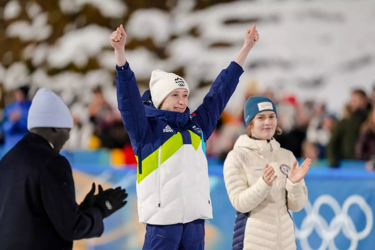 Gold medalist Anna Odine Stroem, of Norway, right, applauds silver medalist Nika Prevc, of Slovenia, on the podium of the ski jumping women's normal hill individual, at the 2026 Winter Olympics, in Predazzo, Italy, Saturday, Feb. 7, 2026. (AP Photo/Evgeniy Maloletka)