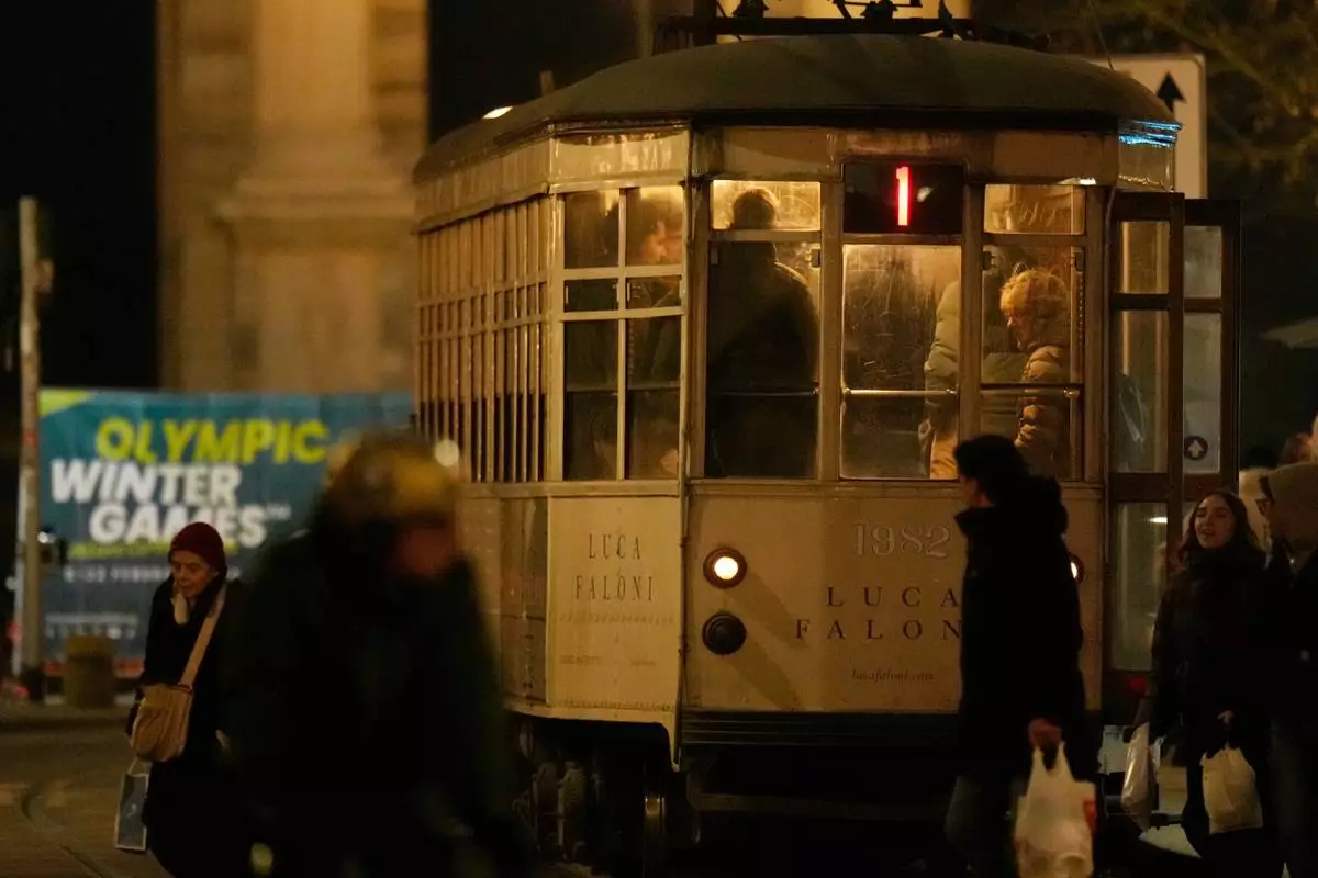 A traditional vintage tram waits for passengers at a stop near to a Milan Cortina Winter Olympics banner, in Milan, Italy, Saturday, Jan. 10, 2026. (AP Photo/Luca Bruno)