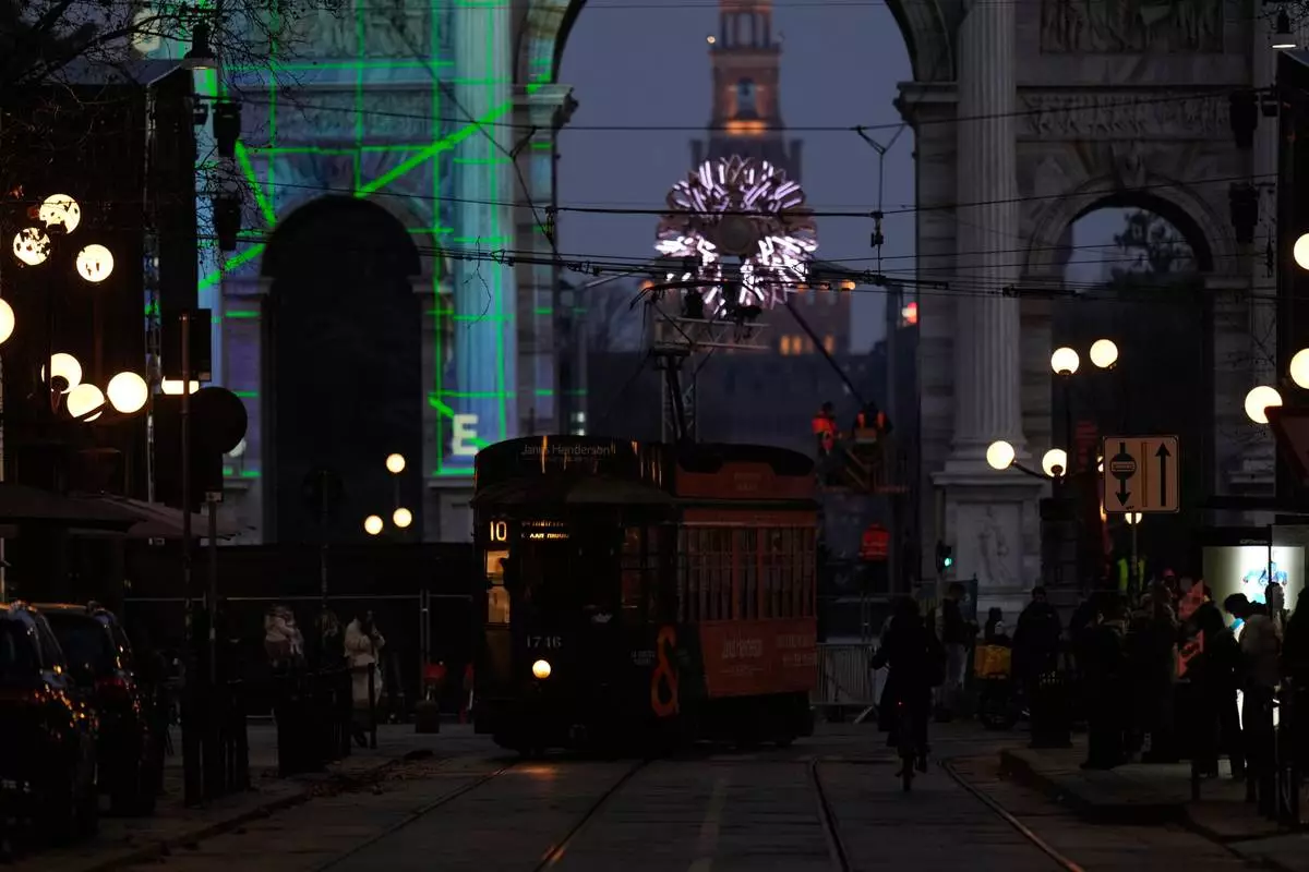 A traditional vintage trams travel on rails through a downtown street near to the Peace Arch, with a view of the Olympic cauldron in the background, ahead of the 2026 Winter Olympics, in Milan, Italy, Saturday, Jan. 31, 2026. (AP Photo/Luca Bruno)