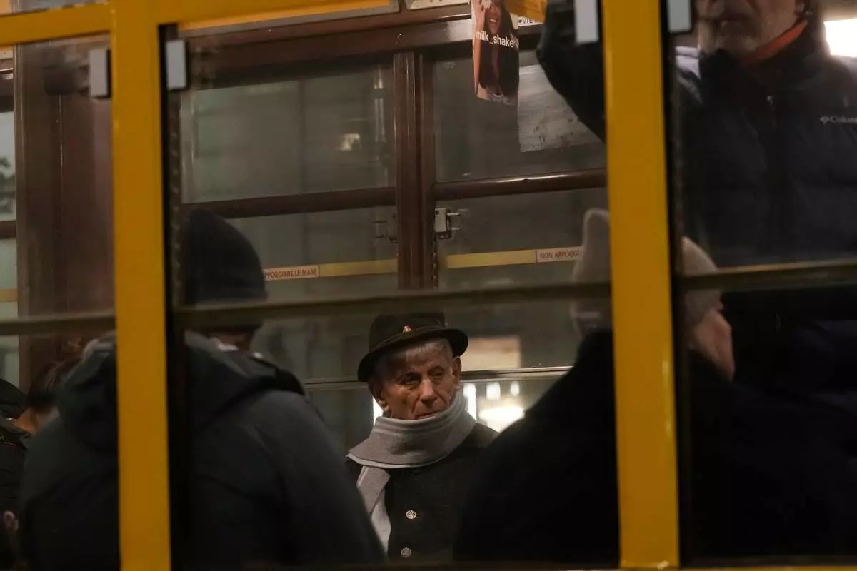 People travel in a traditional vintage tram on rails through a downtown street, in Milan, Italy, Saturday, Nov. 29, 2025. (AP Photo/Luca Bruno)