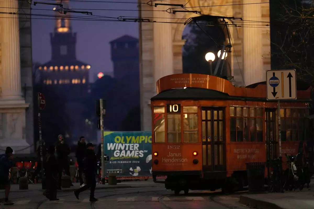 A traditional vintage tram travels on rails at the Peace Arch past a Milan Cortina Winter Olympics banner, in Milan, Italy, Saturday, Jan. 10, 2026. (AP Photo/Luca Bruno)