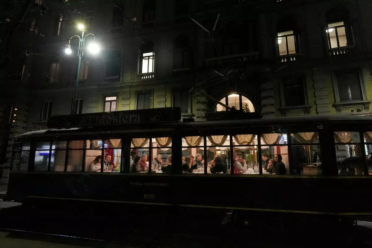 People eat dinner in the 'ATMosfera' restaurant traditional vintage tram traveling on rails through a downtown street, in Milan, Italy, Monday, Dec. 15, 2025. (AP Photo/Luca Bruno)