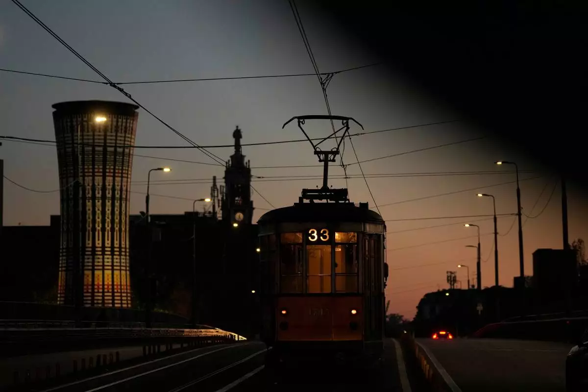 A traditional vintage tram travels on rails near to the Rainbow Tower, a former water tank, through a downtown street, in Milan, Italy, Saturday, Nov. 29, 2025. (AP Photo/Luca Bruno)