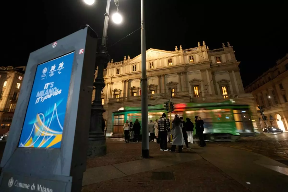 A traditional vintage tram travels on rails by La Scala theatre near to a Milan Cortina Winter Olympics banner, in Milan, Italy, Saturday, Jan. 10, 2026. (AP Photo/Luca Bruno)
