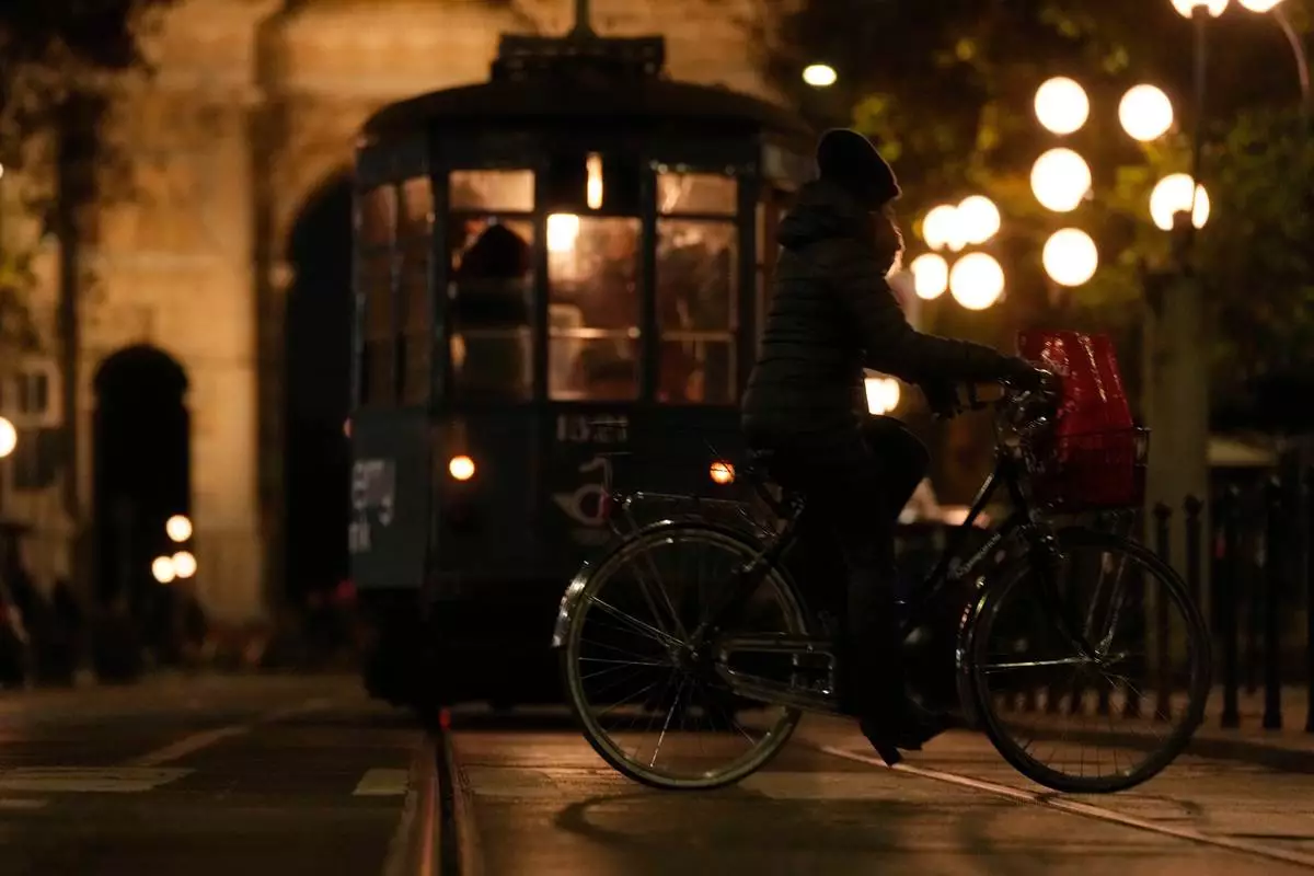 A woman rides her bike past a traditional vintage tram near to the Peace Arch, in Milan, Italy, Saturday, Nov. 29, 2025. (AP Photo/Luca Bruno)
