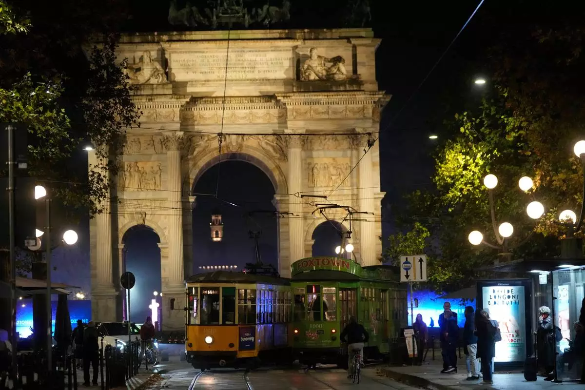 Traditional vintage trams travel on rails through a downtown street near to the Peace Arch, in Milan, Italy, Friday, Nov. 7, 2025. (AP Photo/Luca Bruno)