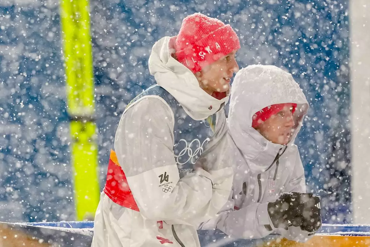 Pawel Wasek, left, and Kamil Stoch, both of Poland, wait while a snowfall interrupts the final round jump of the ski jumping men's super team competition at the 2026 Winter Olympics, in Predazzo, Italy, Monday, Feb. 16, 2026. (AP Photo/Matthias Schrader)