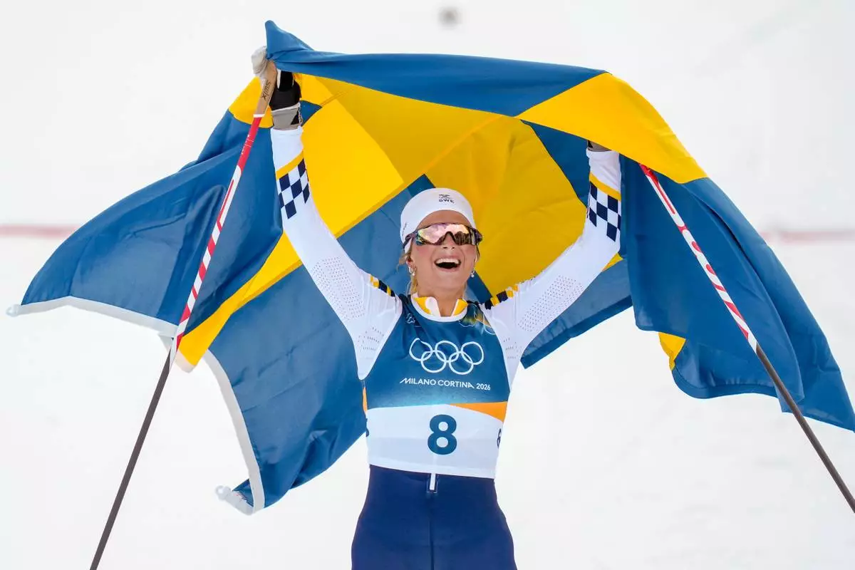 Frida Karlsson of Sweden crosses the finish line to win the gold medal in the cross country skiing women's 10km + 10km skiathlon at the 2026 Winter Olympics, in Tesero, Italy, Saturday, Feb. 7, 2026. (AP Photo/Evgeniy Maloletka)